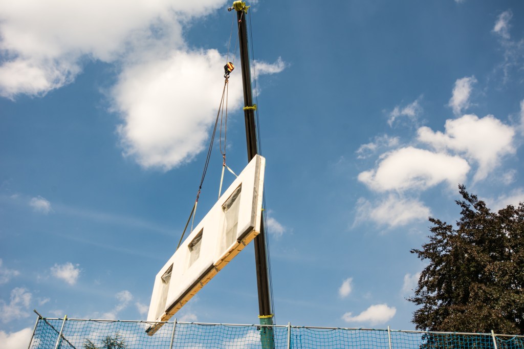A prefabricated home section being lifted into place by crane